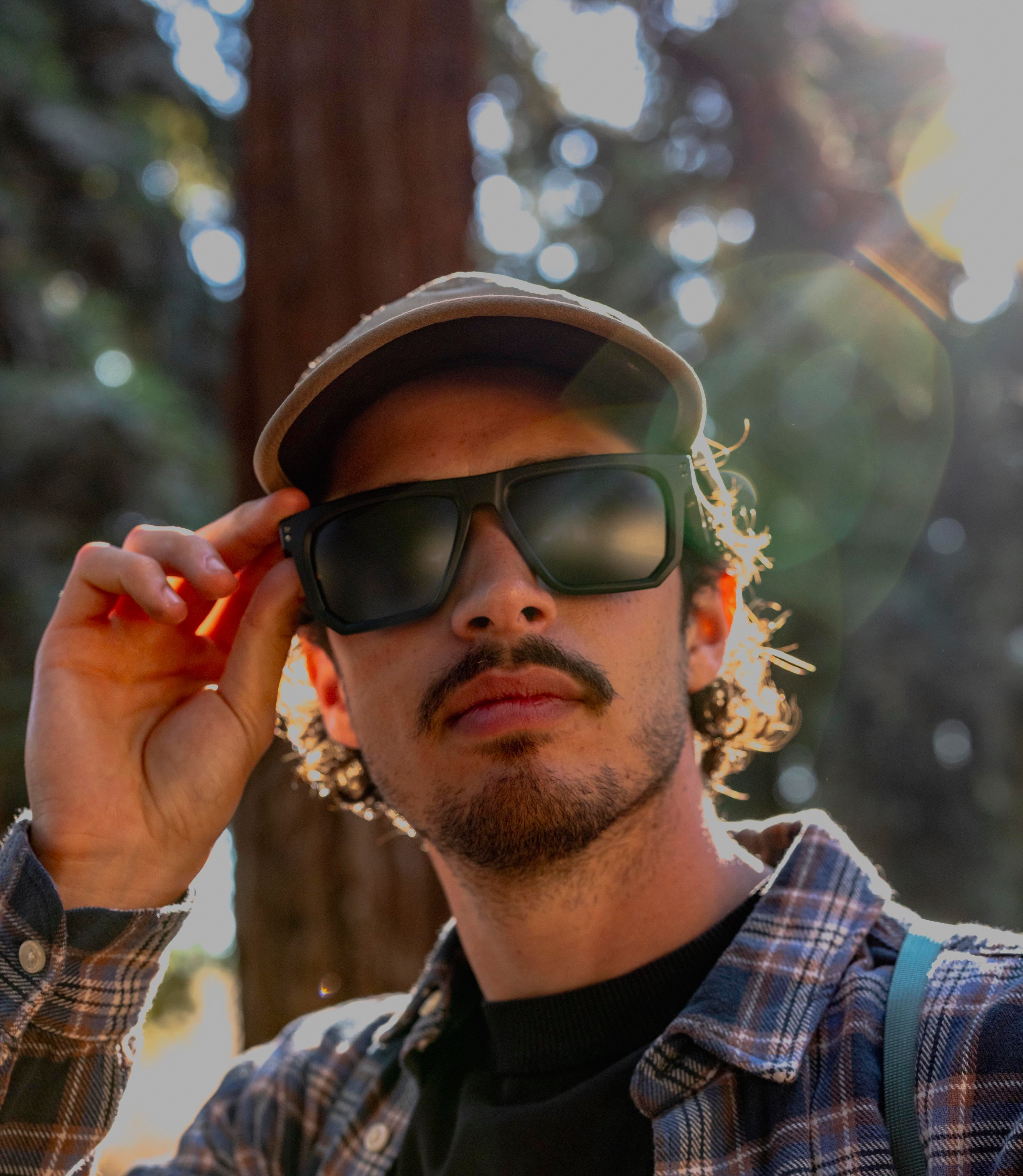 Man wearing sunglasses and a cap with a forest background
